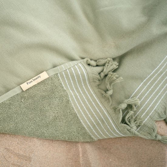 Close-up van de groene hamamdoek met label 'Pure beauty', witte strepen en franjes.
