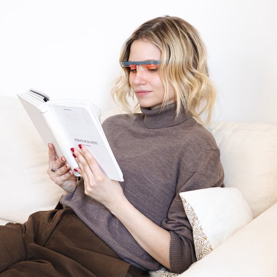 Vrouw leest boek, draagt bril met rood licht.