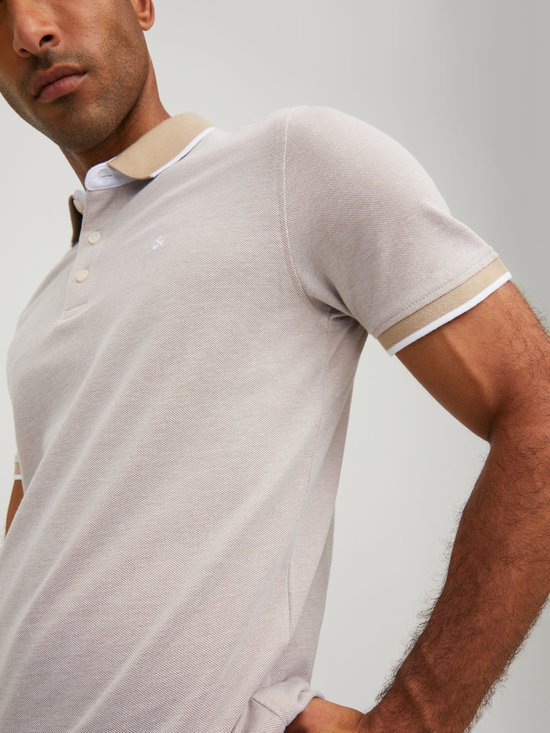 Lichtgrijs poloshirt met beige kraag en witte bies, close-up van de mouw.