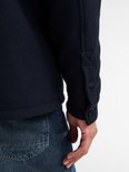 Detail van de mouwboord met twee knopen op een donkerblauw overshirt.