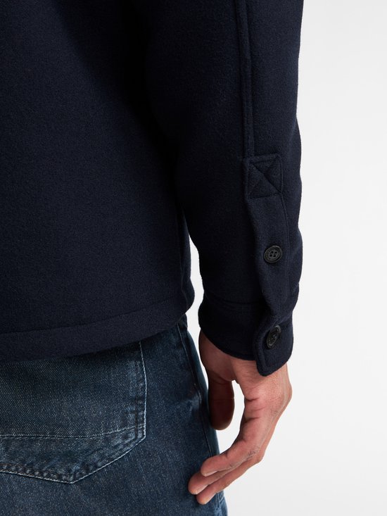 Detail van de mouwboord met twee knopen op een donkerblauw overshirt.