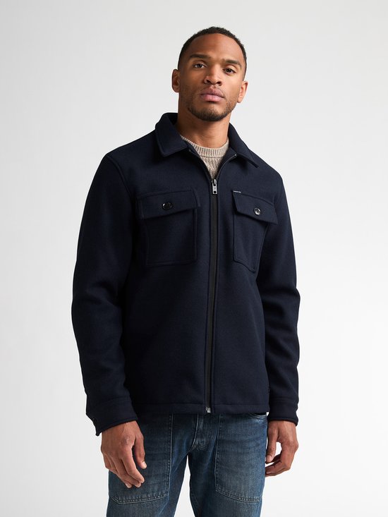 Donkerblauw Petrol Industries overshirt met rits en borstzakken, gedragen over een beige trui.