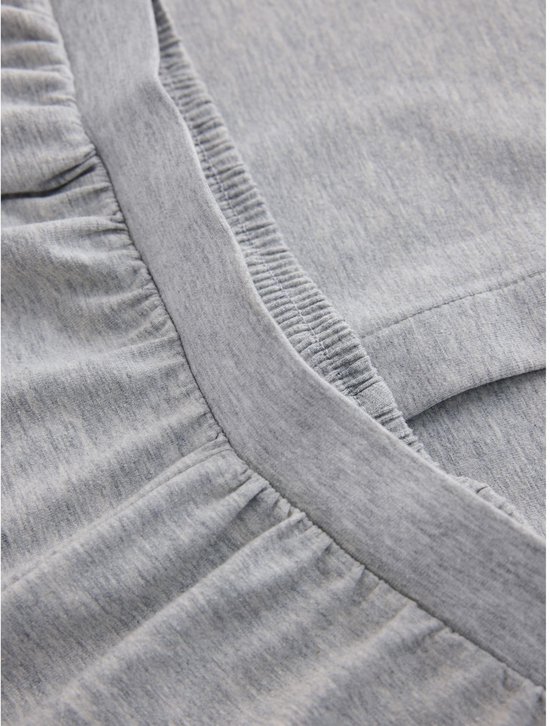 Detail van gerimpelde zoom van grijze jersey stof.