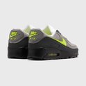 Achterkant van grijze Nike Air Max 90 sneakers met neon groene 'Nike Air' logo op de hiel.