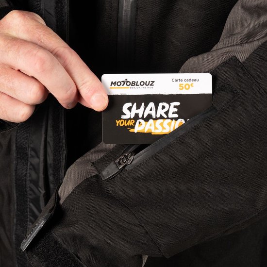 Hand die een 'MOTOGLOUZ' giftcard van 50€ uit een zak van de jas haalt.