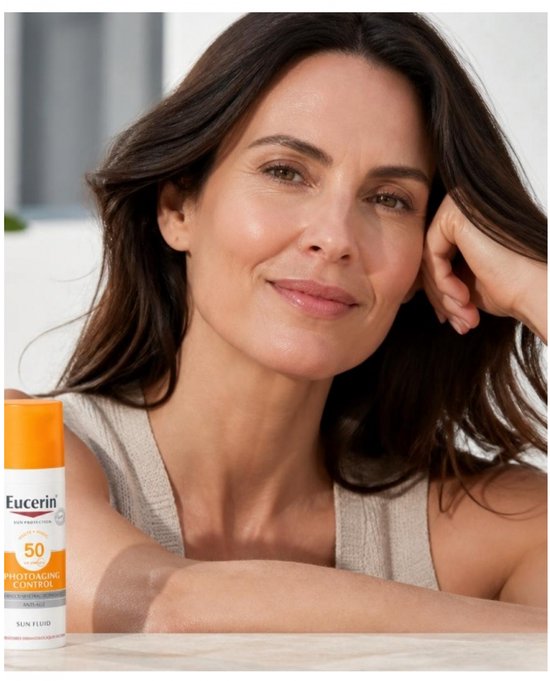 Een vrouw met lang bruin haar, glimlachend, met de Eucerin zonnebrandcrème met SPF 50 naast haar.
