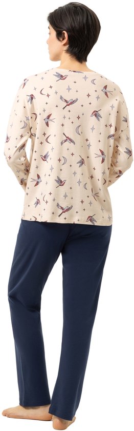 Model met lange mouwen, lichtbeige pyjamashirt met vogels, manen en sterrenprint, gedragen met donkerblauwe pyjamabroek.