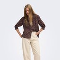 Bruine blouse met witte stippen en driekwart mouwen, gedragen door een model.