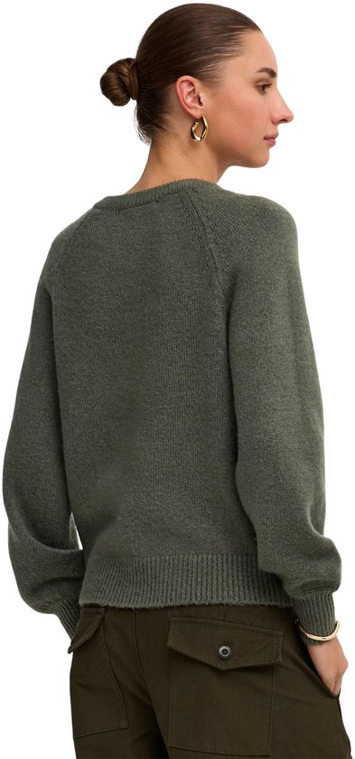 Vrouw in donkergroene trui met ronde hals en broek met cargo zakken, rug zichtbaar.