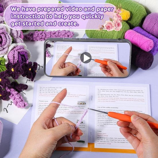 Een smartphone toont een videohandleiding voor het haken van bloemen, met garen, haaknaalden en papieren instructies.