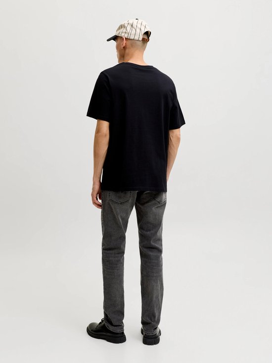 Man met grijze slim fit jeans en zwart T-shirt, van achteren gezien.