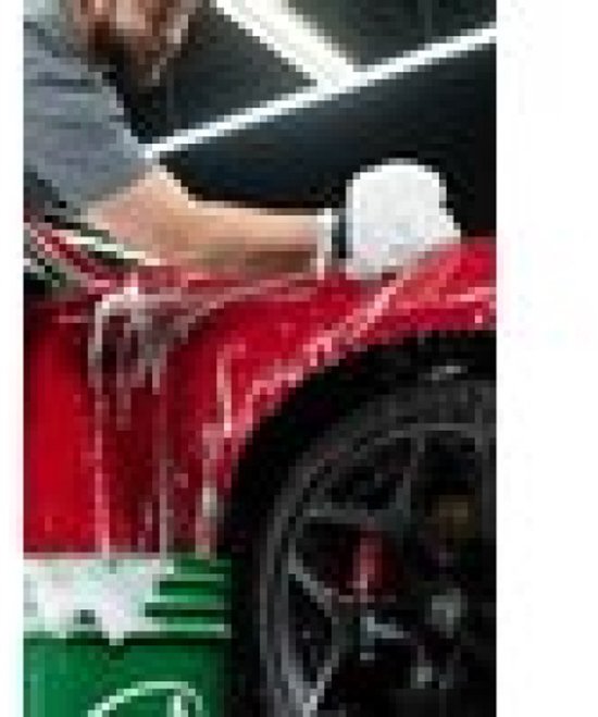 Man wast een rode auto met schuimend autoshampoo.
