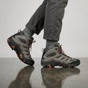 Olijfgroene Merrell Moab 3 wandelschoenen met grijze broek en grijze sokken, zijaanzicht.