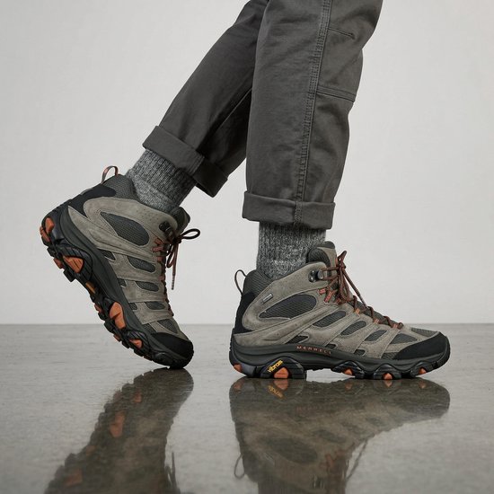 Olijfgroene Merrell Moab 3 wandelschoenen met grijze broek en grijze sokken, zijaanzicht.