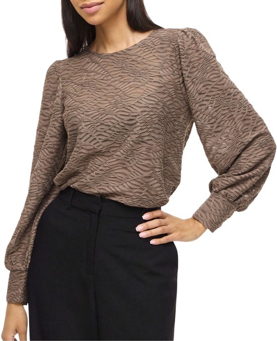 Model draagt een bruine top met golvend patroon en pofmouwen.