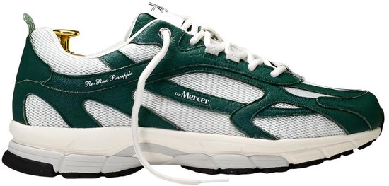 Zijprofiel van een witte sneaker met groene overlays. De schoen heeft mesh panelen en 'the Mercer'-logo.