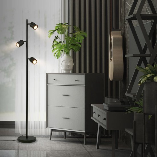 Zwarte staande lamp met drie verstelbare spots, in een woonkamer met meubels.