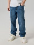 Jongen in een witte t-shirt en losse, blauwe jeans.