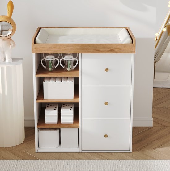 Witte commode met houten accenten, drie laden met gouden knoppen en drie open planken.