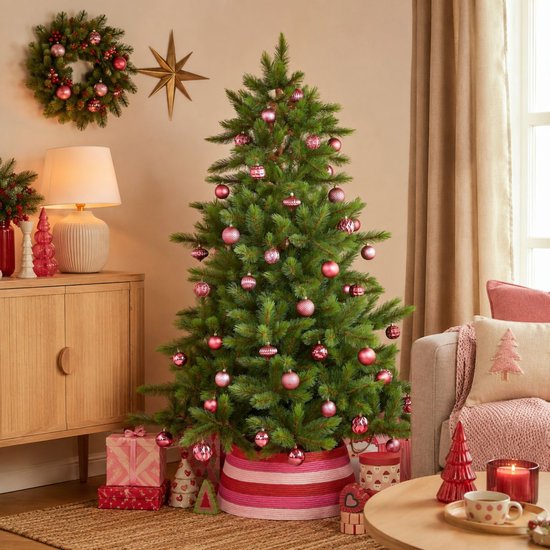Versierde Triumph Tree kunstkerstboom met roze ballen in een gezellige woonkamer.