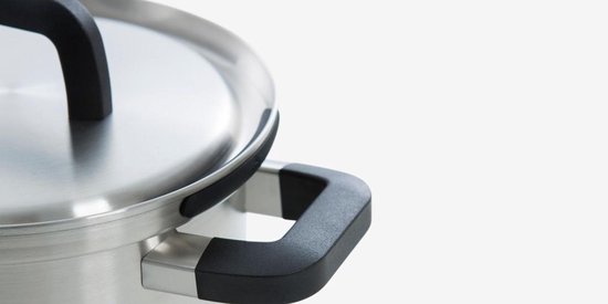 Close-up van de rand van een roestvrijstalen pan met een zwart handvat en deksel.