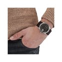 Man met bruine trui en spijkerbroek draagt een zilverkleurig Diesel horloge met donkerbruine leren band.