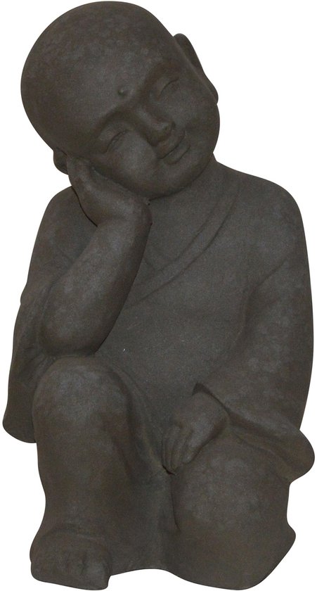 Statue de Bouddha enfant en pierre gris foncé, assis en tailleur, tête sur la main.