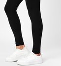 Voeten van een model in zwarte zwangerschapslegging met witte sneakers