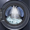 Gros plan du tambour ouvert d'une machine à laver bleu foncé, avec éclairage LED et quelques serviettes bleu clair à l'intérieur.