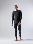 Man staat model voor zwarte longsleeve en thermobroek met fijne ribbelstructuur.