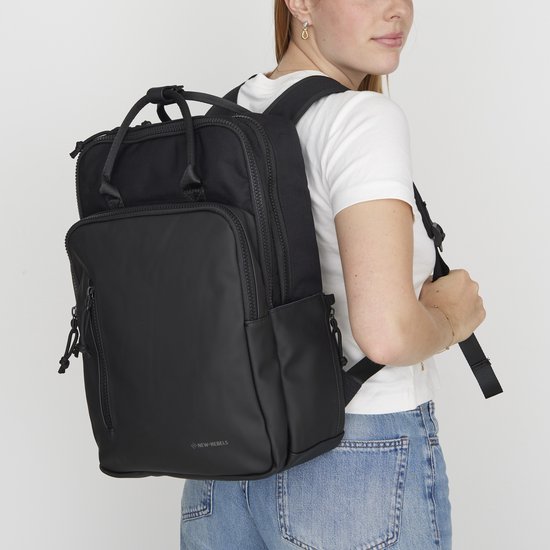 Vrouw met een zwarte rugzak, draagt hem over haar schouder.