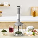 Grijze Tefal staafmixer met een hakmolen gevuld met kruiden, een maatbeker met rode vloeistof en een kom met ijs.