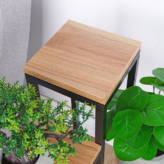Houten bovenblad met zwart metalen frame, omringd door groene planten.