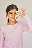 Een jong meisje met een roze trui houdt een regenboogkleurig Plus-Plus bouwwerk voor haar oog.