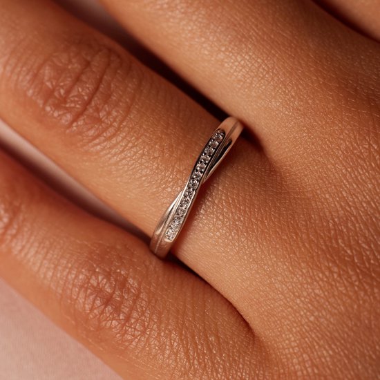 Vinger met een zilverkleurige ring met gedraaid design en zirkonia.