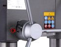 Grijze boormachine met 3 metalen hendels en een zwarte instelschroef.