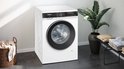 Siemens iQ500 wasmachine in een moderne badkamer met plant en stapels kleding.
