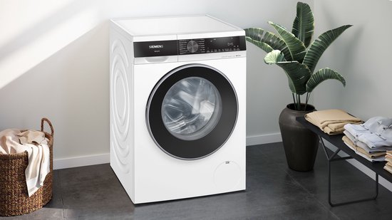 Siemens iQ500 wasmachine in een moderne badkamer met plant en stapels kleding.