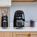 Zwarte SMEG koffiemolen en filterkoffiemachine met glazen kannen.