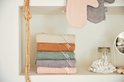 Stapel van zes badcapes in beige, bruin, groen, grijs en roze, naast een spiegel.