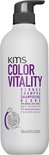 Witte fles KMS Color Vitality Blonde Shampoo met zwarte pomp en granaatappel illustratie.