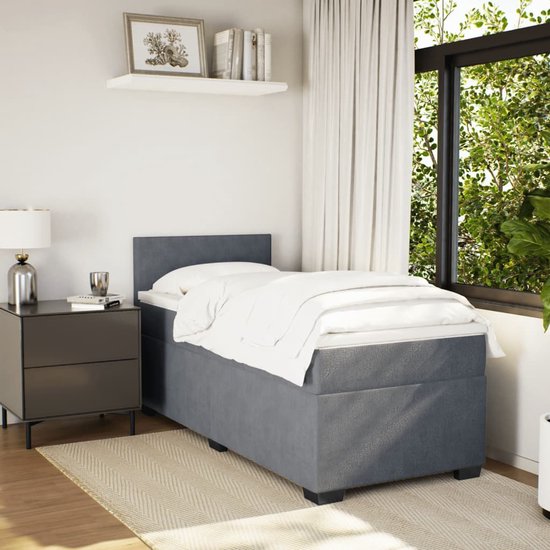 Lit boxspring gris foncé avec couettes blanches, dans une chambre.