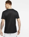 Homme aux cheveux roux avec tatouage sur le bras, vu de dos, portant un t-shirt de sport noir et un short blanc.