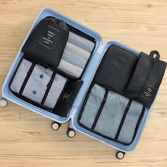 Zwarte packing cubes en een toilettas georganiseerd in een open, lichtblauwe koffer.