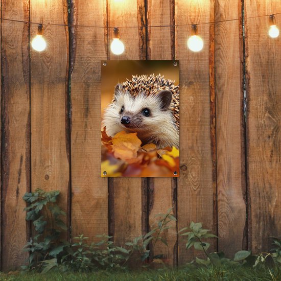 Een egel in herfstbladeren hangt aan een houten schutting met verlichting.