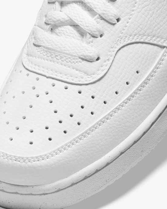 Close-up van de voorkant van een witte Nike sneaker, met stiksels en perforaties.
