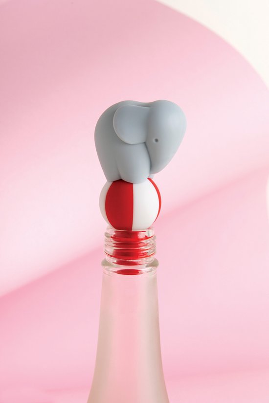 Grijze olifant op een rode en witte bal, bovenop een fles, in een roze setting.