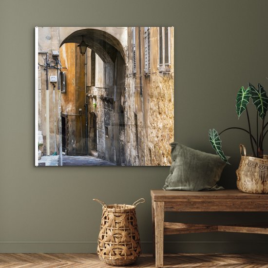 ® Glasschilderij 90x90 cm - Schilderij acrylglas - Stenen boog in een steegje tijdens een zonnige dag - Foto op glas - Muurdecoratie woonkamer - Wanddecoratie slaapkamer - Schilderijen