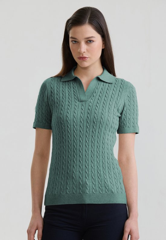 Femme portant un polo vert menthe à manches courtes avec un motif torsadé.
