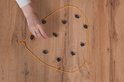 Een hand met een ring plaatst een magneet op een gele lijn op een houten tafel.